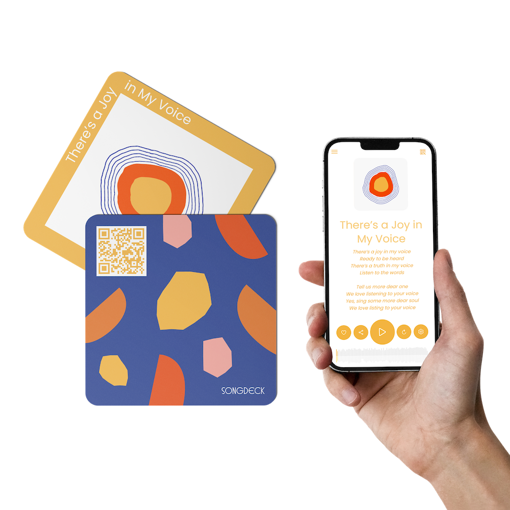 A hand holding a phone running the Songdeck app, playing the card 'There is Joy in My Voice', next to the card itself